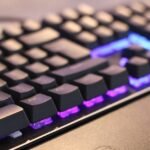 Angled view of a backlit mechanical keyboard glowing in the dark.