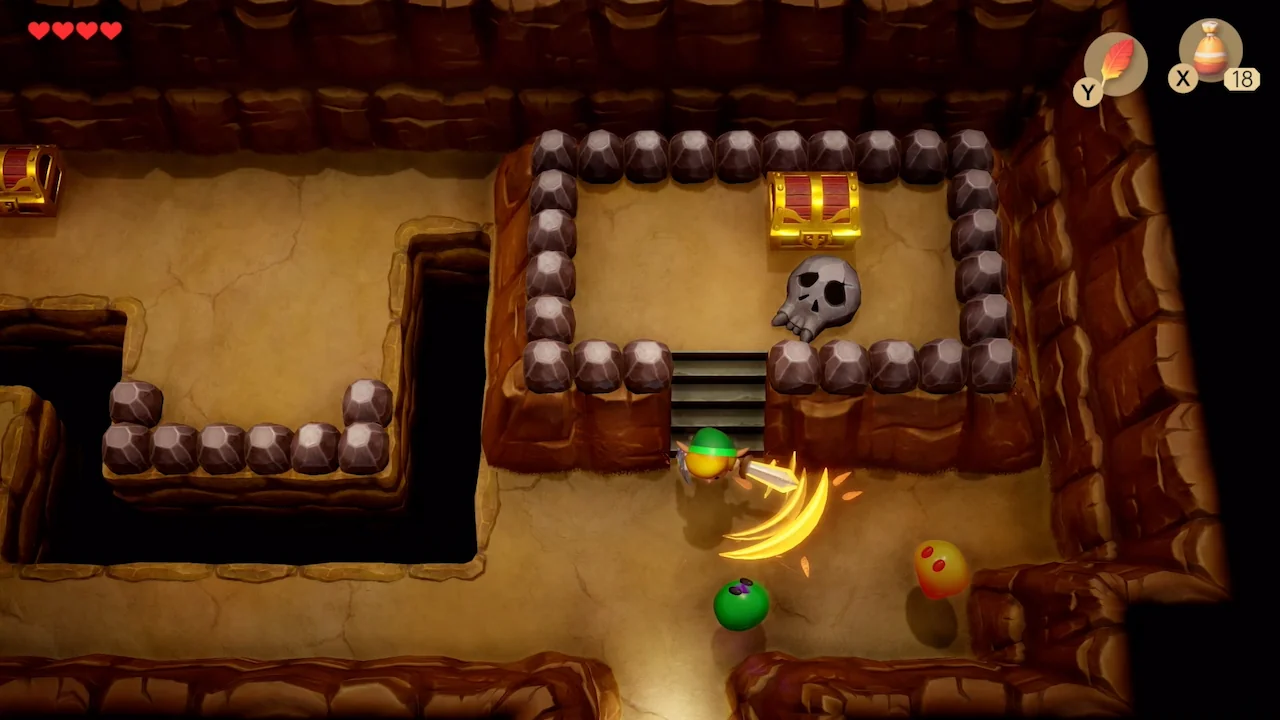 Link swings his sword in a cave, striking a blob enemy in The Legend of Zelda: Link’s Awakening (2019)