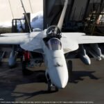 In-engine imagery from **Ace Combat 8 Wings of Theve** showing the protagonist's F/A-18E Super Hornet carrier-based fighter in a hangar bay.