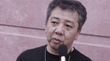 Yoshihisa Kishimoto, creator of the Double Dragon and Kunio-kun series, speaking into a microphone during an interview.