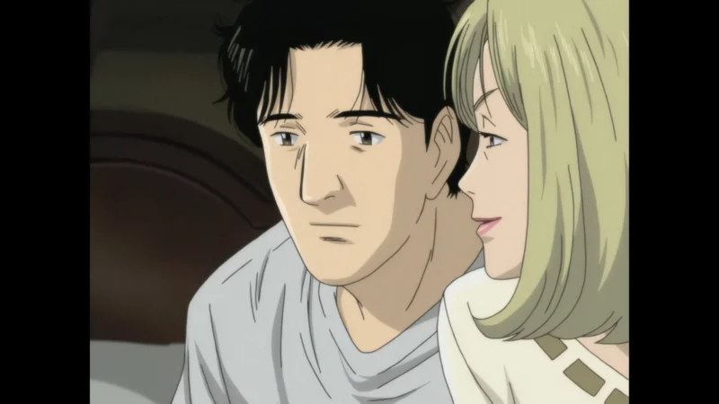 Blu-ray screenshot from Naoki Urasawa's Monster showing Dr. Kenzo Tenma talking to a blonde woman.