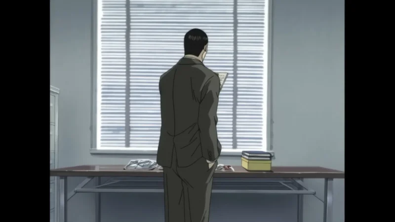 Blu-ray screenshot showing the back of a man in a brown suit looking out of office blinds.