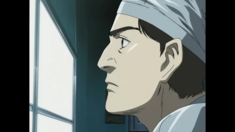 Blu-ray screenshot profile shot of Dr. Kenzo Tenma in surgical gear looking out a hospital window.